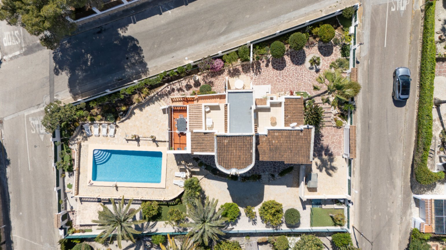 Luftaufnahme des 1030 m² großen Eckgrundstücks mit privatem Pool, gepflegten mediterranen Gärten und der Villa mit ihren verschiedenen Terrassenebenen.