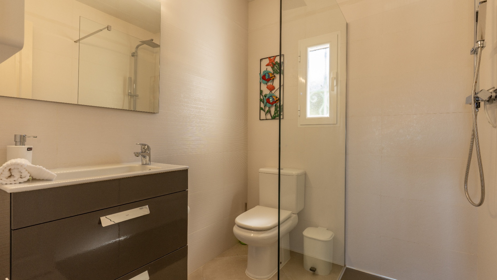 Modernes Badezimmer mit dunkelgrauem Waschtisch, großem Spiegel und begehbarer Dusche mit Glastrennwand und verchromten Armaturen.