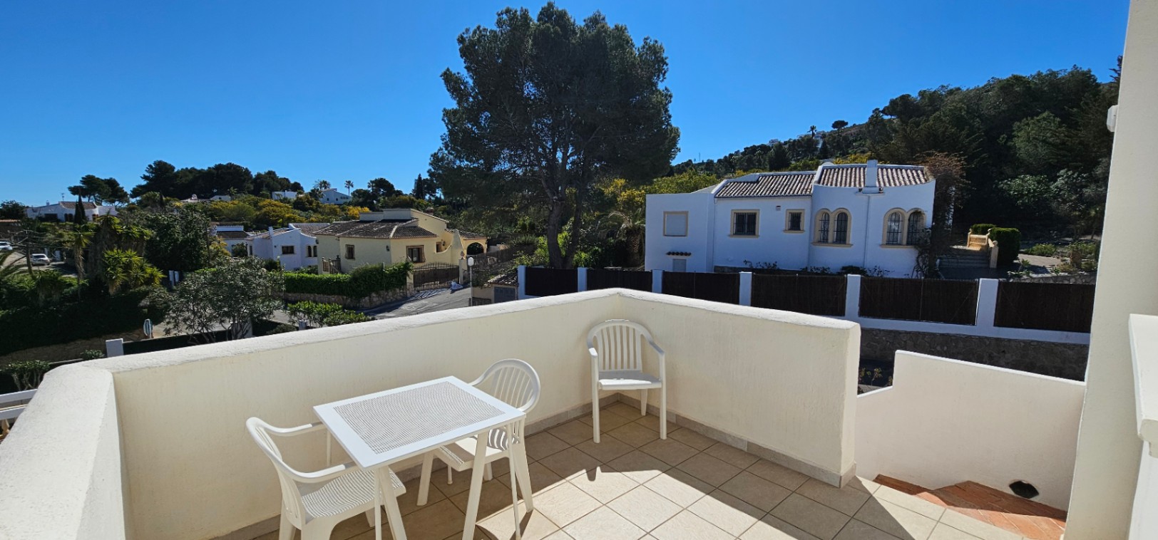 Offene Dachterrasse mit Fliesenboden und Außenmöbeln, die einen weiten Blick über das Wohngebiet Pinosol und die umliegenden Hügel bietet.