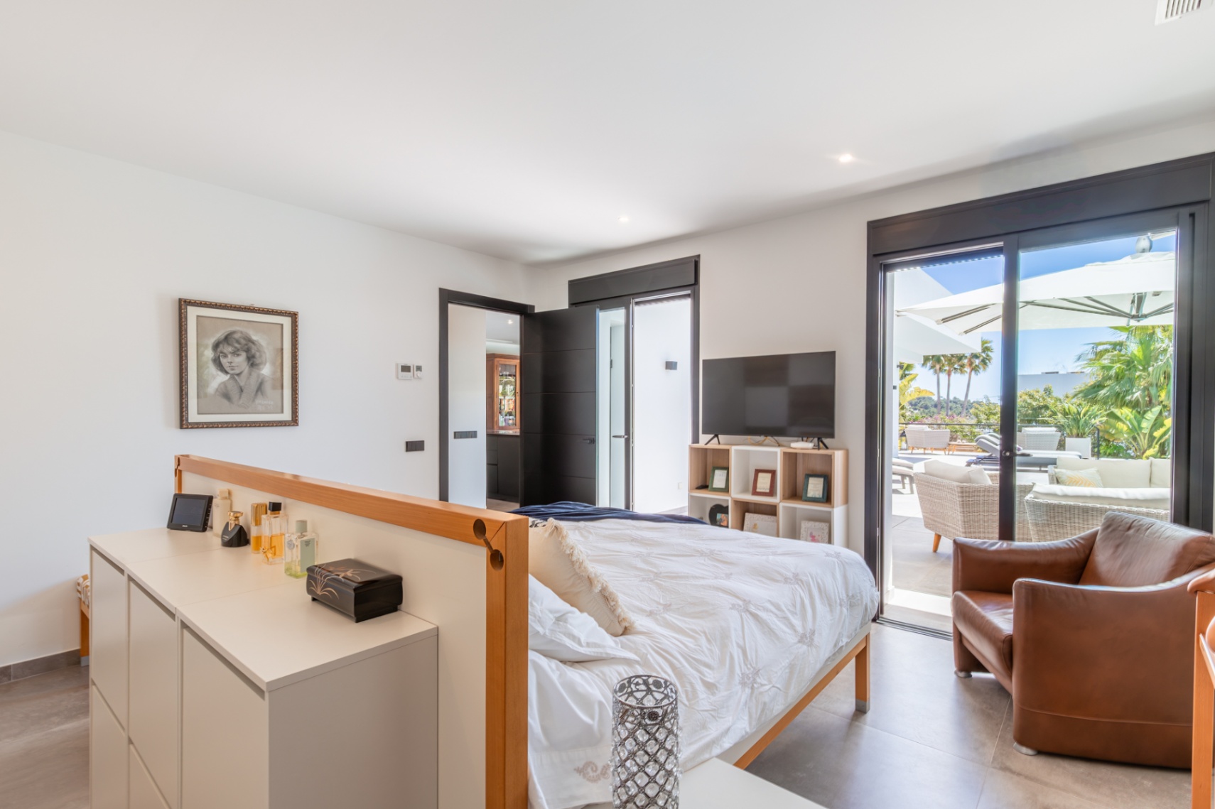 Hauptschlafzimmer mit direktem Terrassenzugang, großen Glasschiebetüren, integrierten Stauraumlösungen und hellem, offenem Raumkonzept mit Blick ins Grüne.