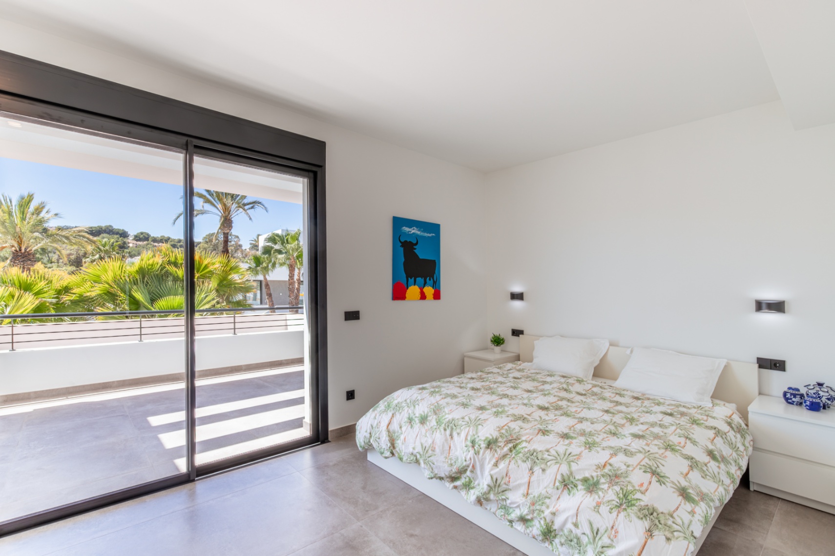 Helles Schlafzimmer mit direktem Zugang zu einer privaten Terrasse durch große Glasschiebetüren. Grauer Fliesenboden und minimalistisches Design mit Wandleuchten.