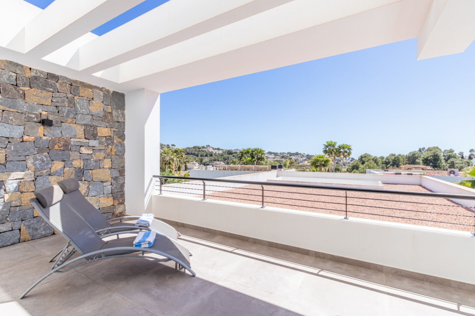 Private Terrasse im Obergeschoss mit weißer Pergola, Natursteinwand und weitem Blick über die umliegende Landschaft von Moraira.
