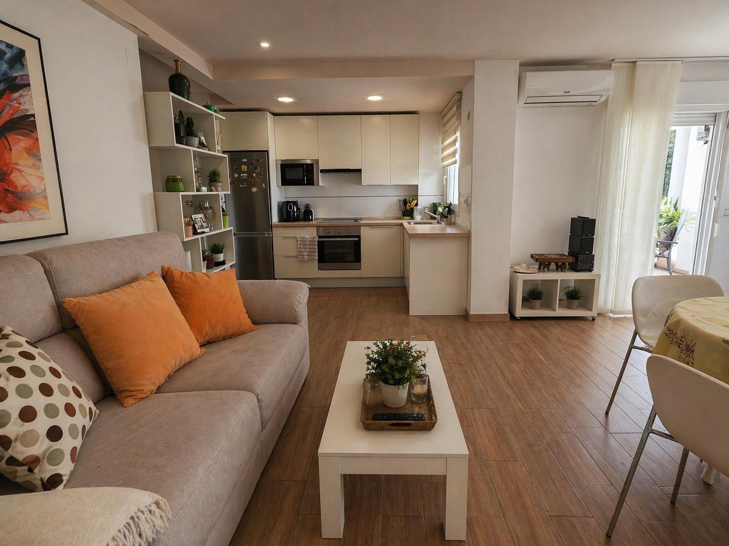 Offener Wohn- und Essbereich mit Fliesen in Holzoptik, moderner Einbauküche und direktem Zugang zum Balkon, ausgestattet mit einer Klimaanlage.