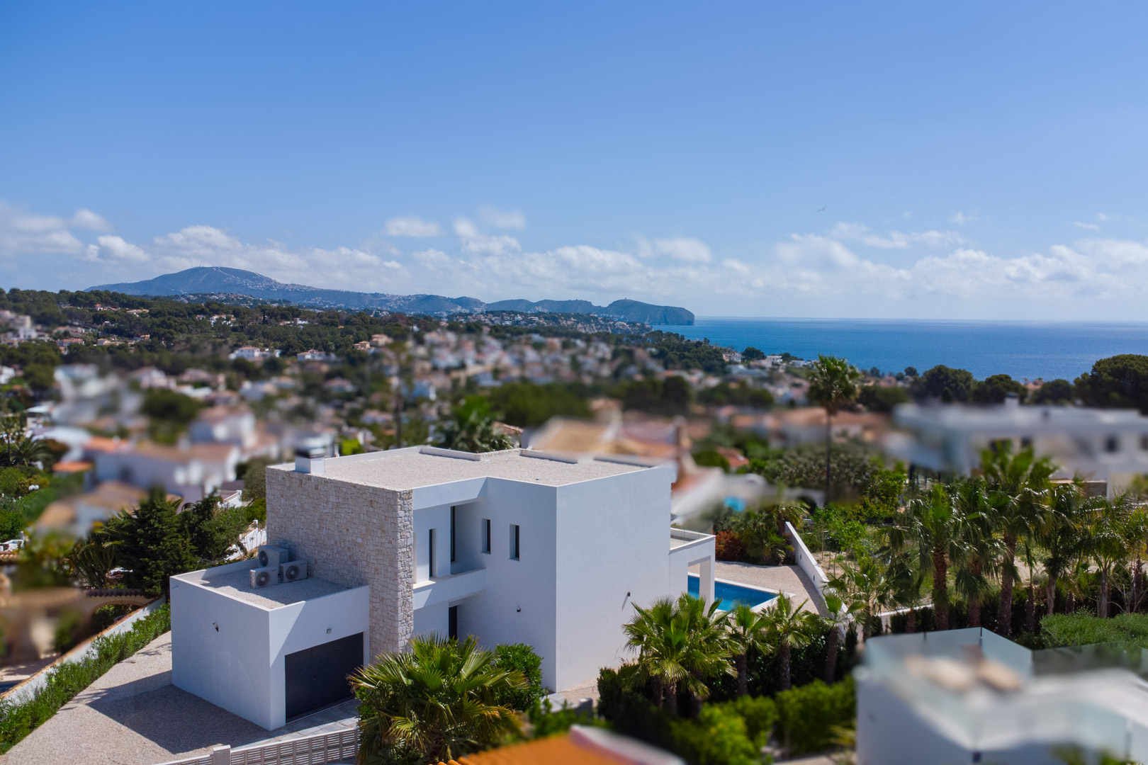 Erhöhte Ansicht der modernen Villa mit Natursteinfassade, privatem Pool und weitem Blick auf das Mittelmeer in La Fustera.