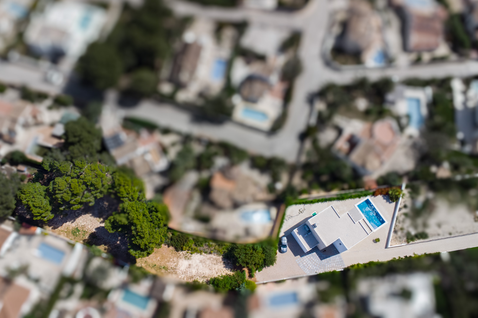 Luftaufnahme der modernen Villa auf dem großzügigen, flachen Grundstück mit rechteckigem Pool und funktionaler Außenanlage in der Wohngegend von Benissa.
