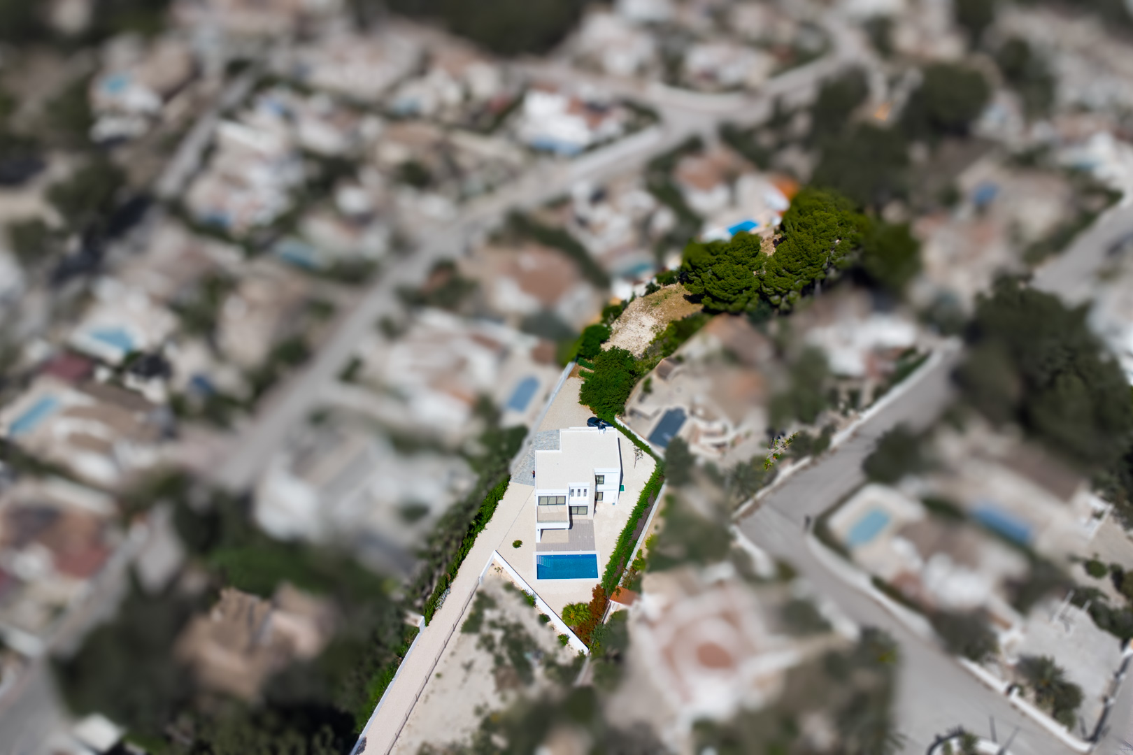 Luftaufnahme der modernen Villa auf einem weitläufigen, ebenen Grundstück mit rechteckigem Pool und einer großen zusätzlichen Gartenfläche in Benissa.