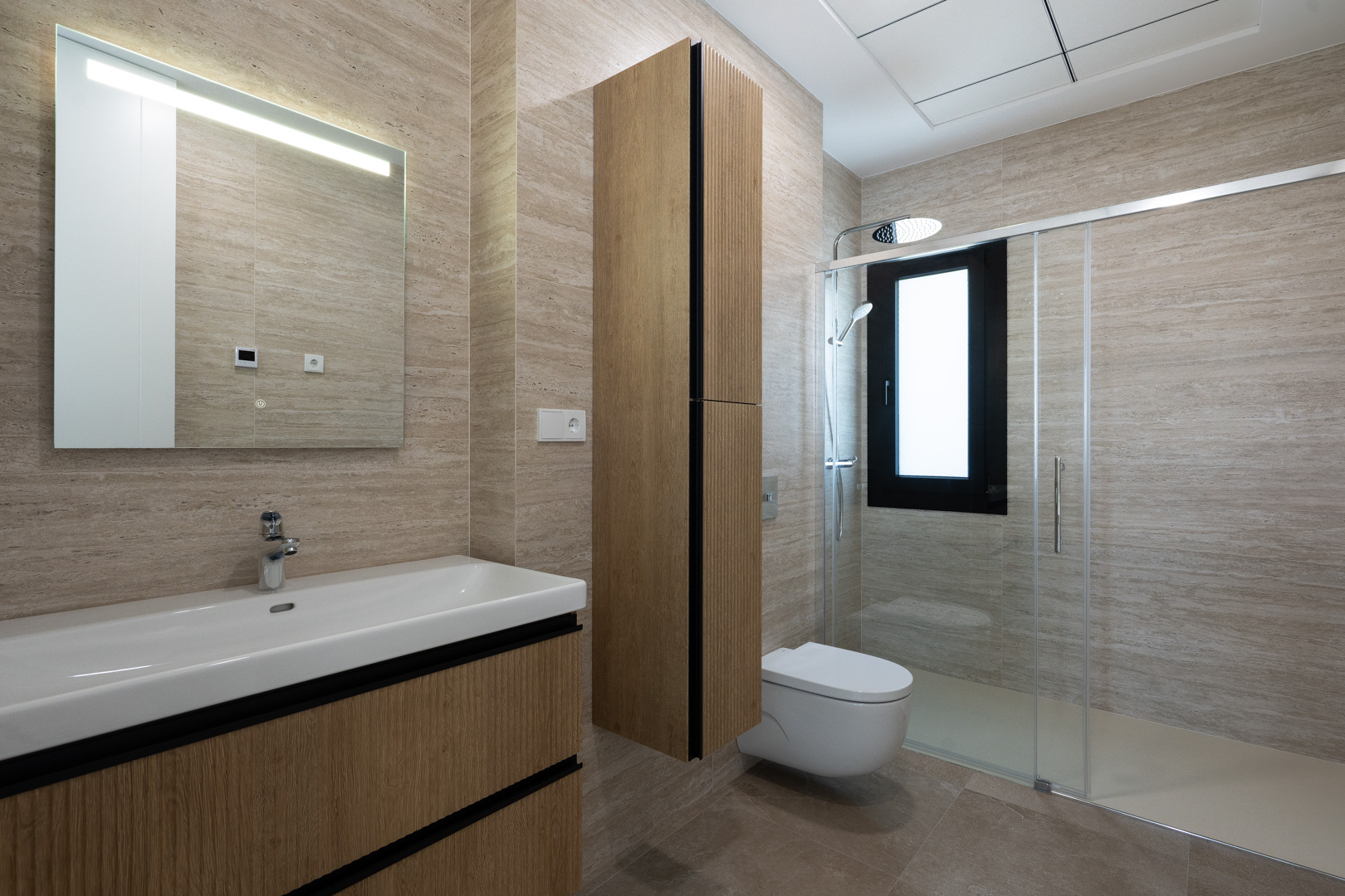 Modernes Badezimmer mit strukturierten Feinsteinzeugfliesen, schwebendem Waschtisch in Holzoptik, Wand-WC und begehbarer Dusche mit Glastrennwand.