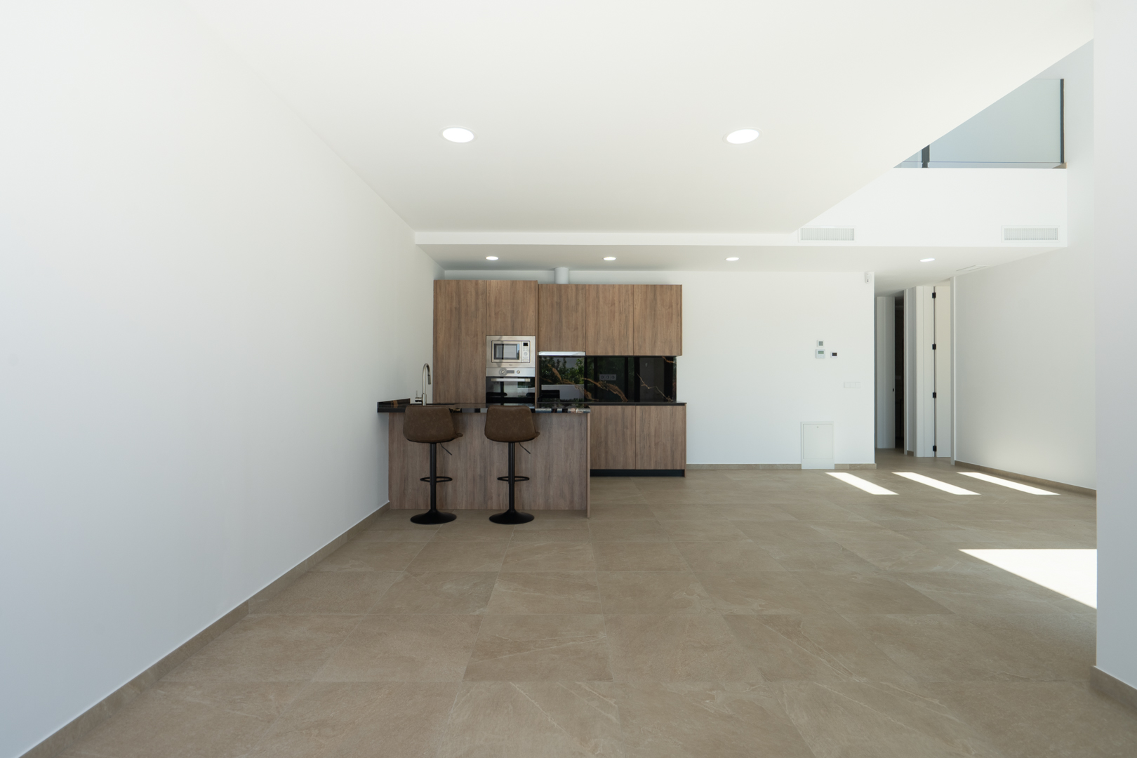 Offene Designerküche mit Holzfronten, dunkler Arbeitsplatte und Frühstücksbar in einem großzügigen Wohnbereich mit Feinsteinzeugböden und doppelter Deckenhöhe.