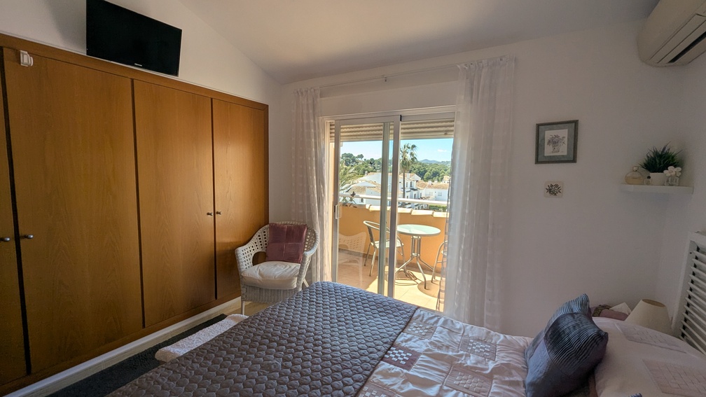 Hauptschlafzimmer mit großem Einbauschrank aus Holz, Klimaanlage und Glasschiebetüren, die auf eine private Terrasse mit Panoramablick führen.