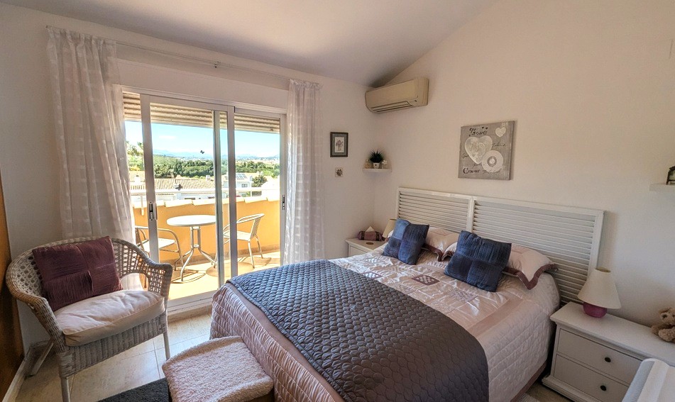 Helles Hauptschlafzimmer mit Dachschräge, Klimaanlage und direktem Zugang zur privaten Terrasse mit weitem Blick auf die umliegende Landschaft.