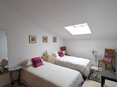 Helles Zweibettzimmer mit Dachschräge und Oberlicht, das viel Tageslicht spendet. Ausgestattet mit zwei Einzelbetten, Nachttisch und Fliesenboden.