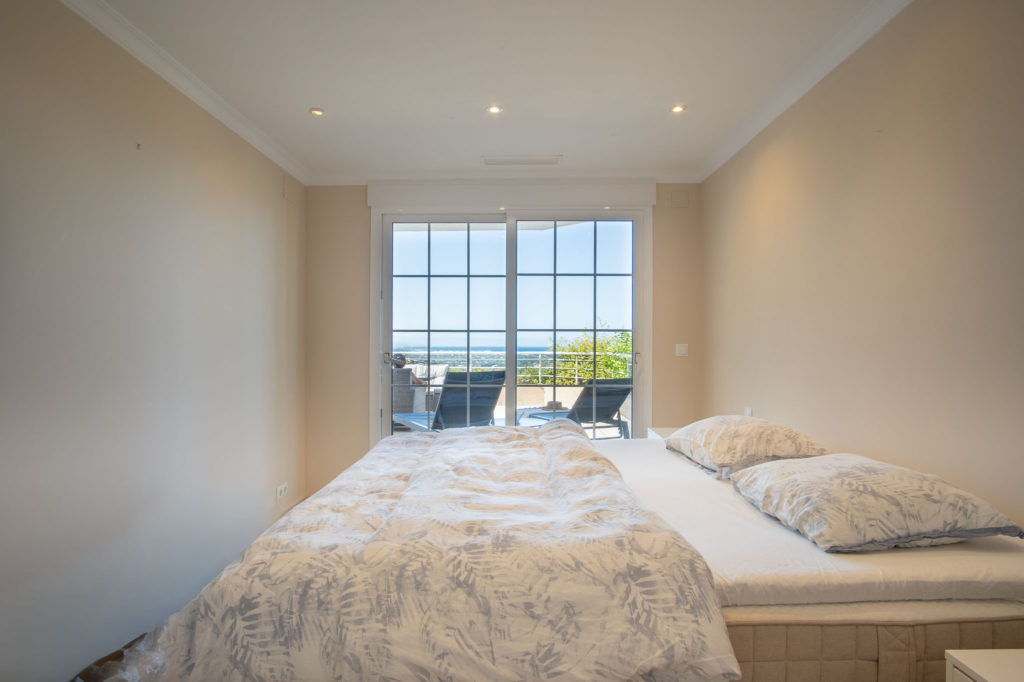 Doppelzimmer mit direktem Zugang zur Terrasse durch Fenstertüren mit Sprossen, Panoramablick auf das Meer und Deckeneinbaustrahlern.