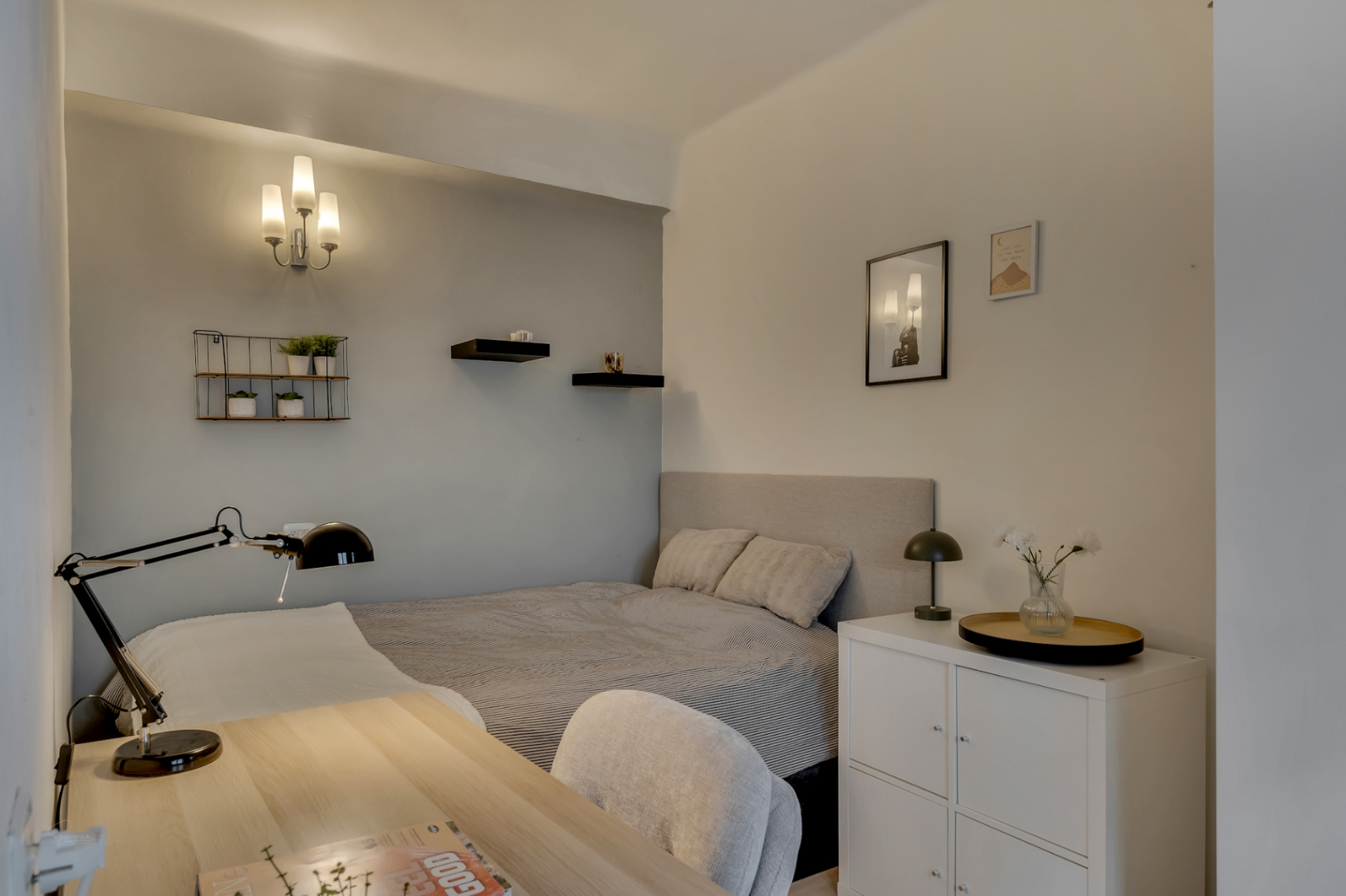 Helles Schlafzimmer mit hellem Holzschreibtisch und dekorativen Wandregalen.