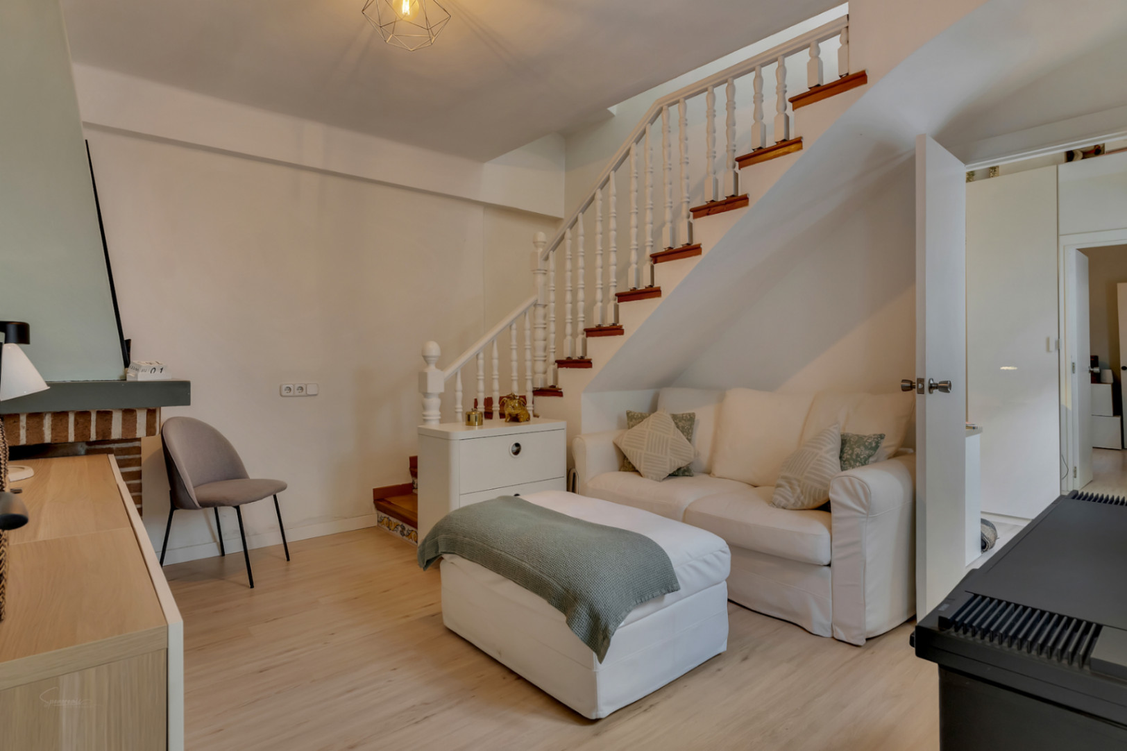 Helles Wohnzimmer mit weißer Holztreppe und weißem Sofa. Moderne und minimalistische Einrichtung.