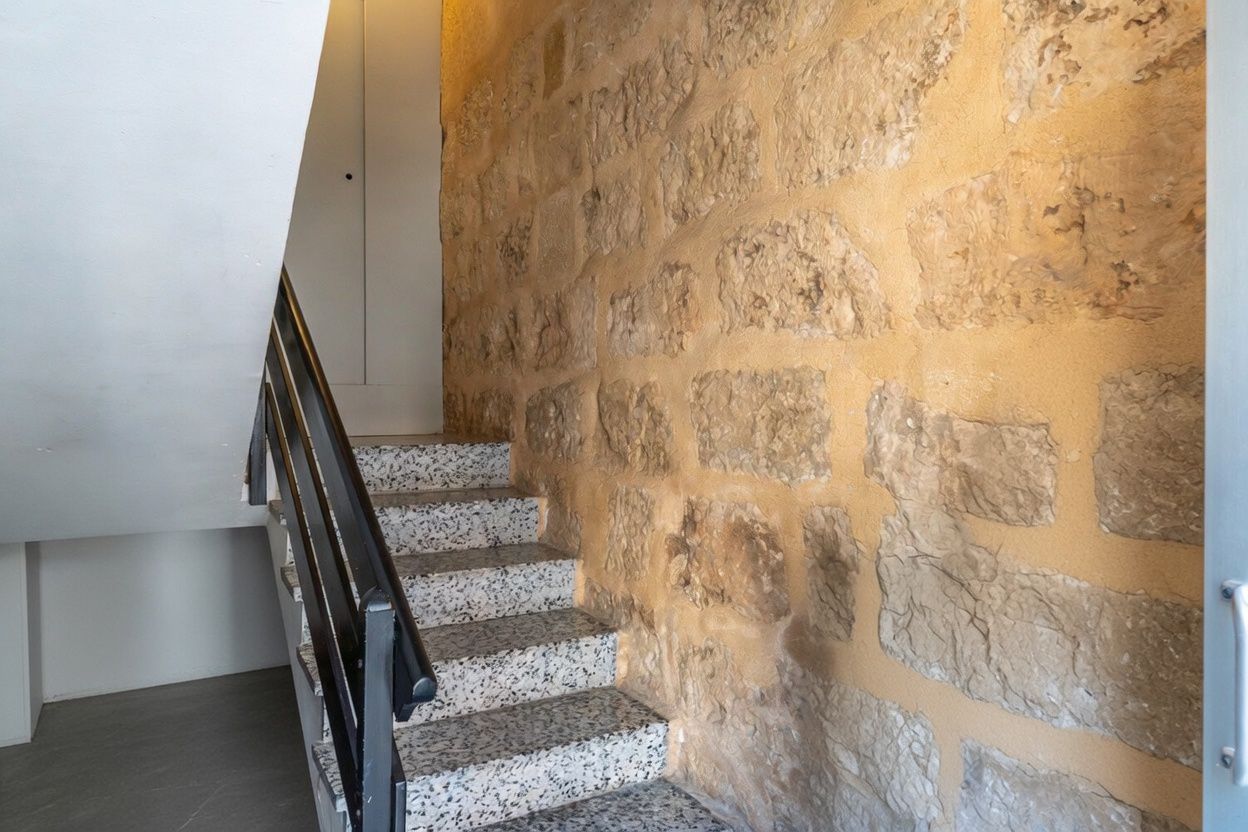 Treppendetail mit freiliegender Steinwand und Terrazzostufen.