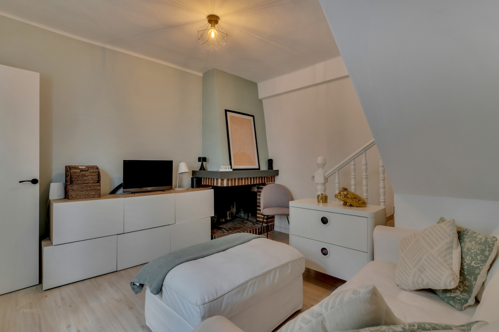 Wohnzimmer mit Backsteinkamin, weißen Möbeln und hellem Holzboden.