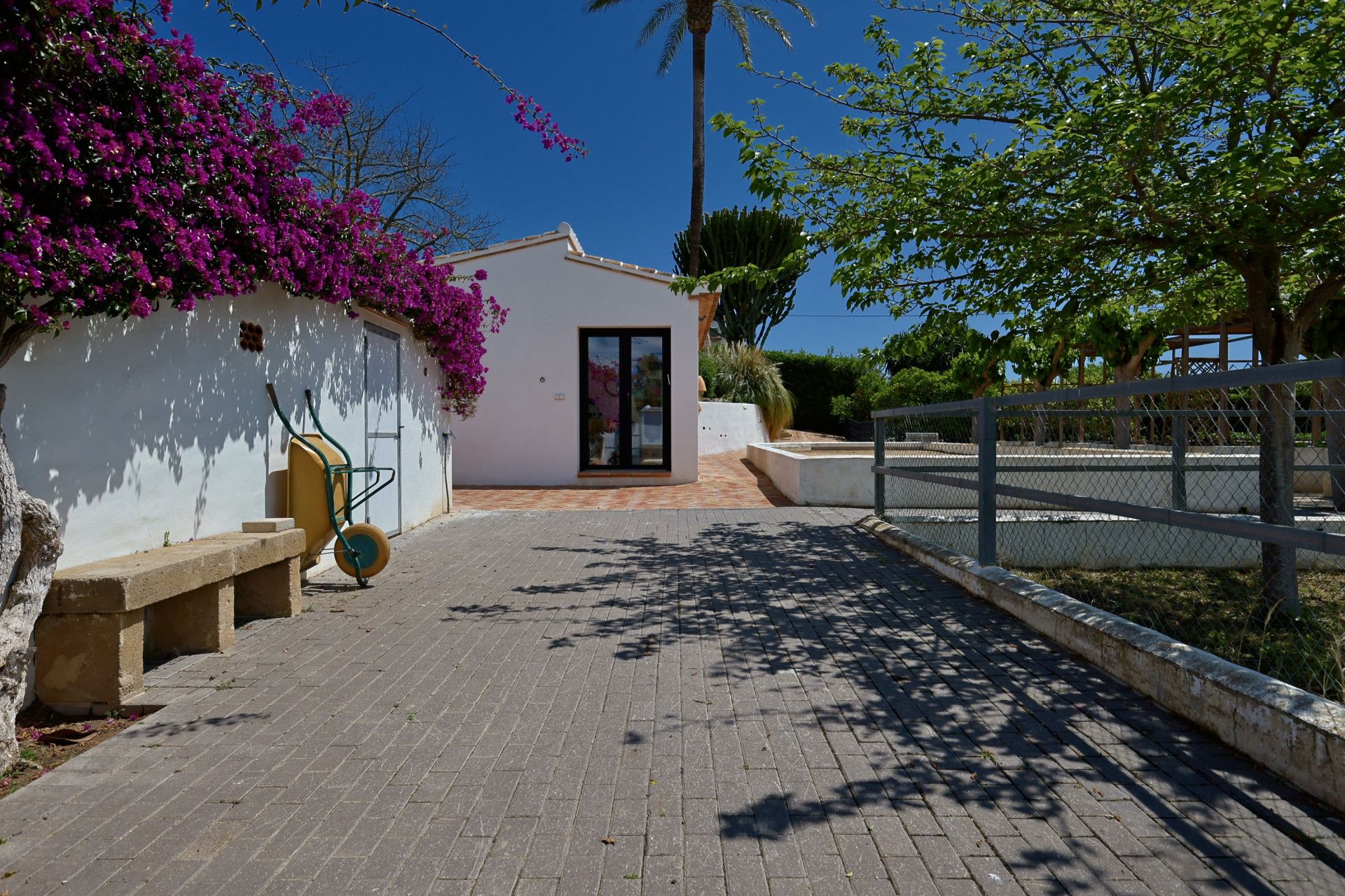 Villeneingang mit Bougainvillea und Steinbank.