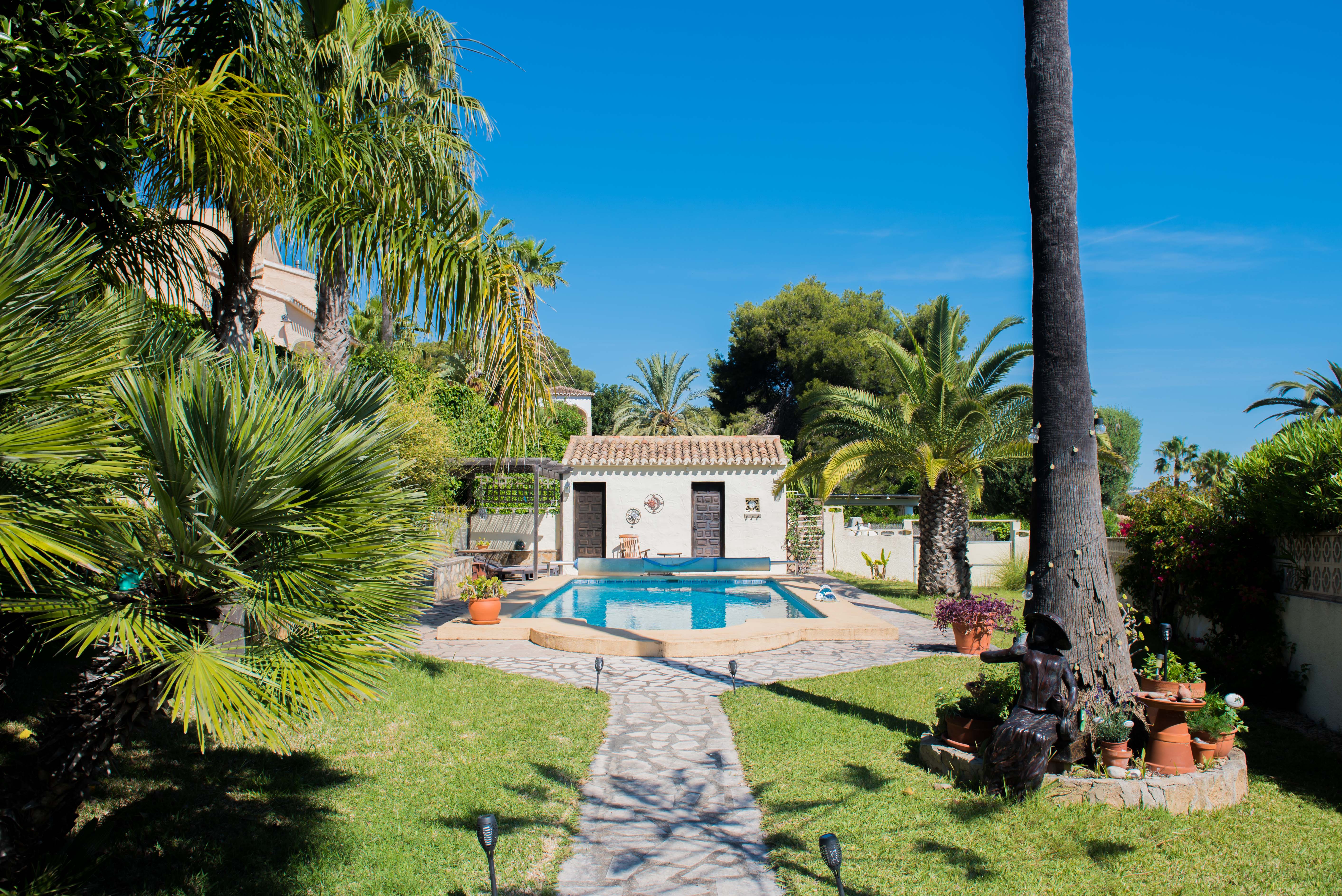 Blick auf den 8x4 m Pool mit Wärmepumpe, umgeben von Gärten und einer ausgestatteten Sommerküche in Jávea.