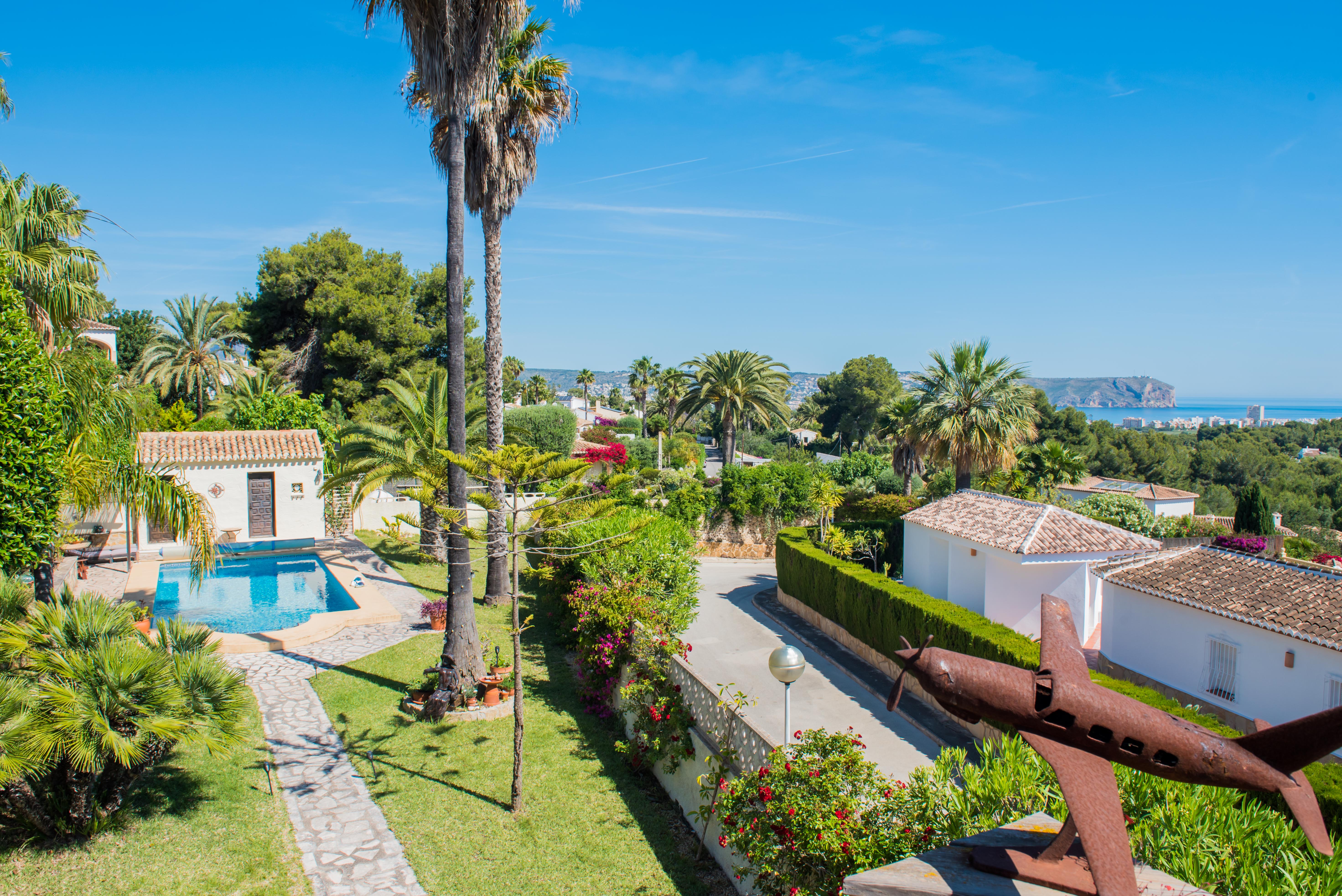 Erhöhte Ansicht des mediterranen Gartens mit Pool und verrosteter Flugzeugskulptur in Jávea.