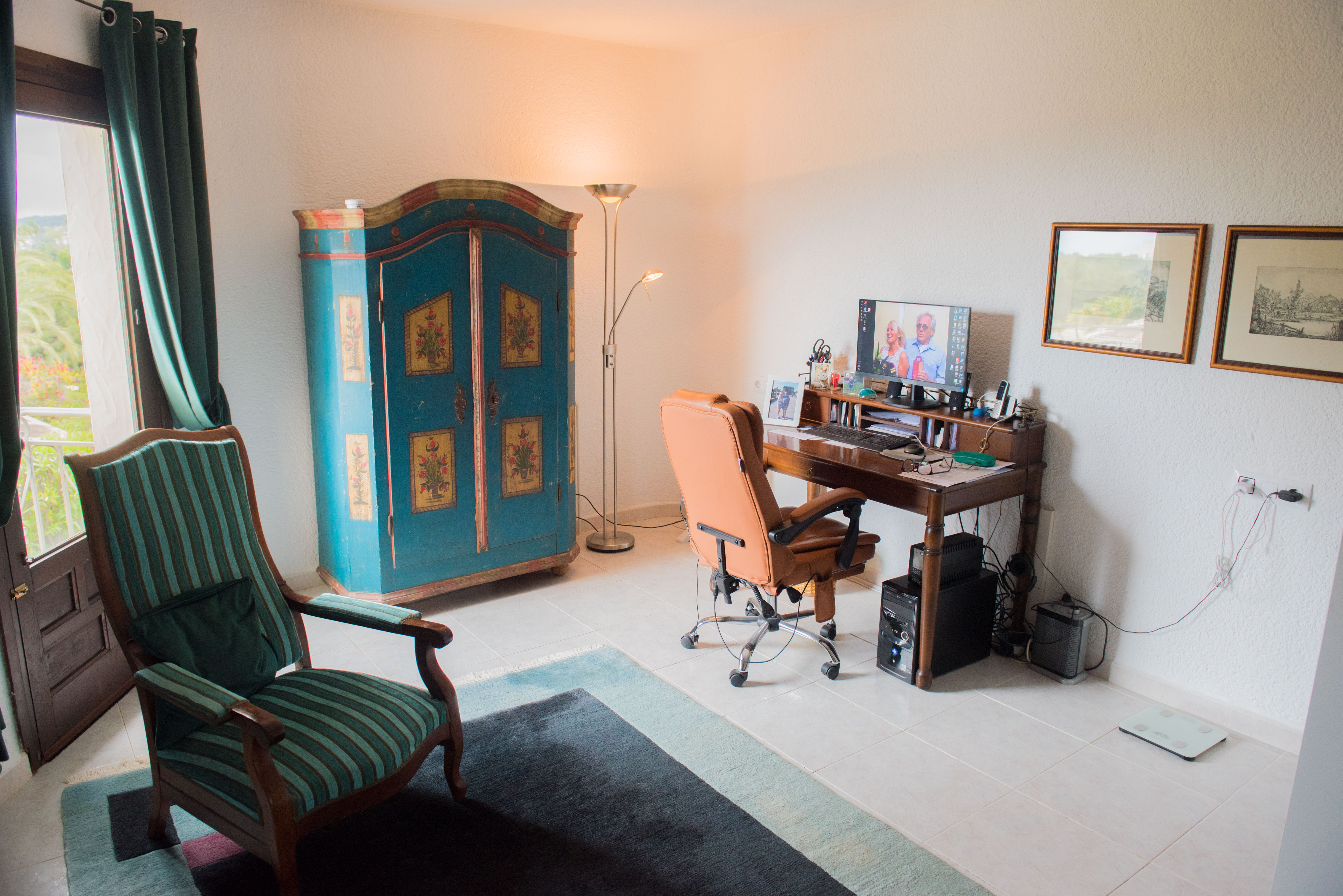 Funktionelles Arbeitszimmer mit klassischem Holzschreibtisch, rustikalem Schrank und Ledersessel. Mit natürlichem Licht und direktem Terrassenzugang.
