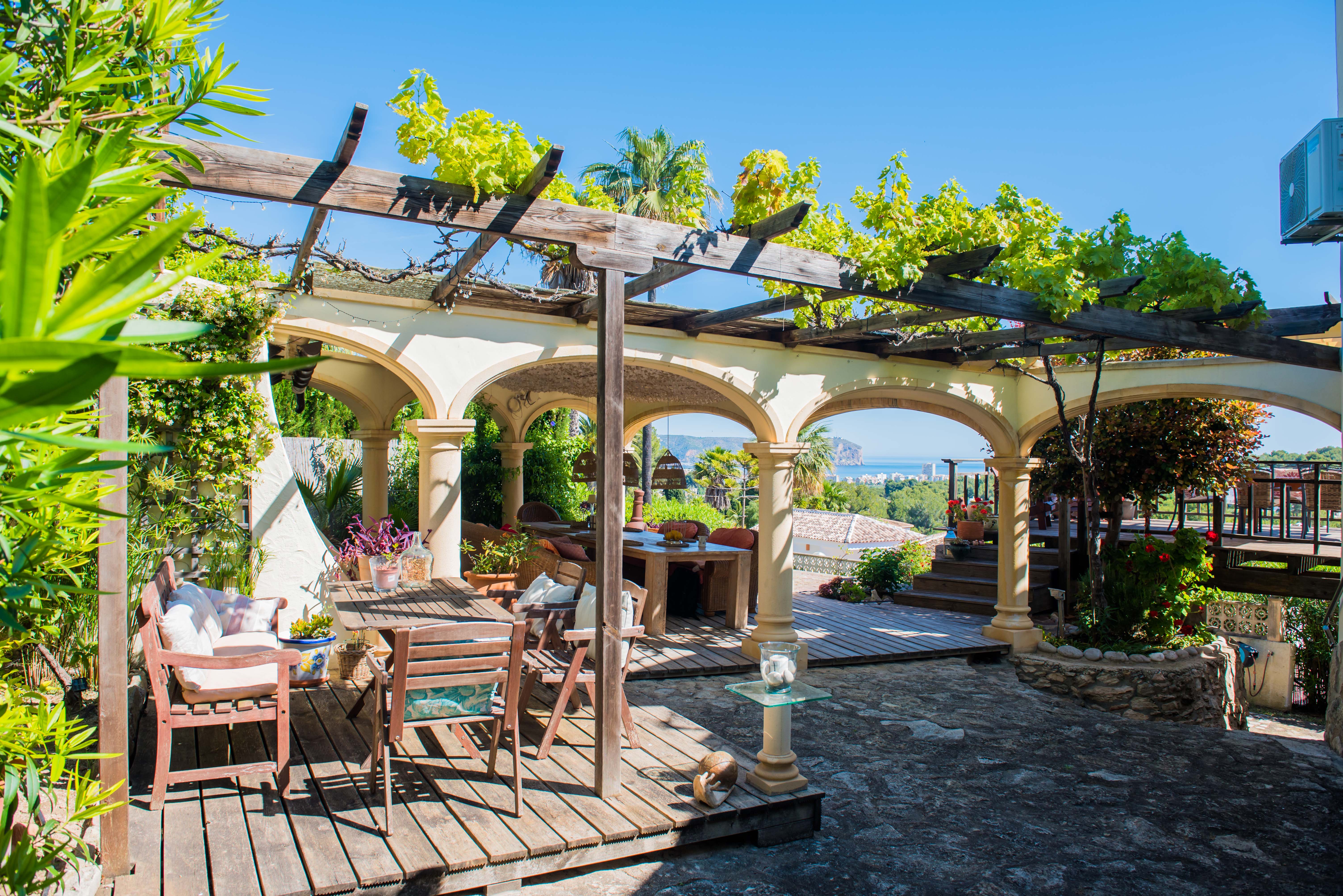 Terrasse mit holzgedeckter Pergola und Steinbögen mit Blick auf das Mittelmeer.