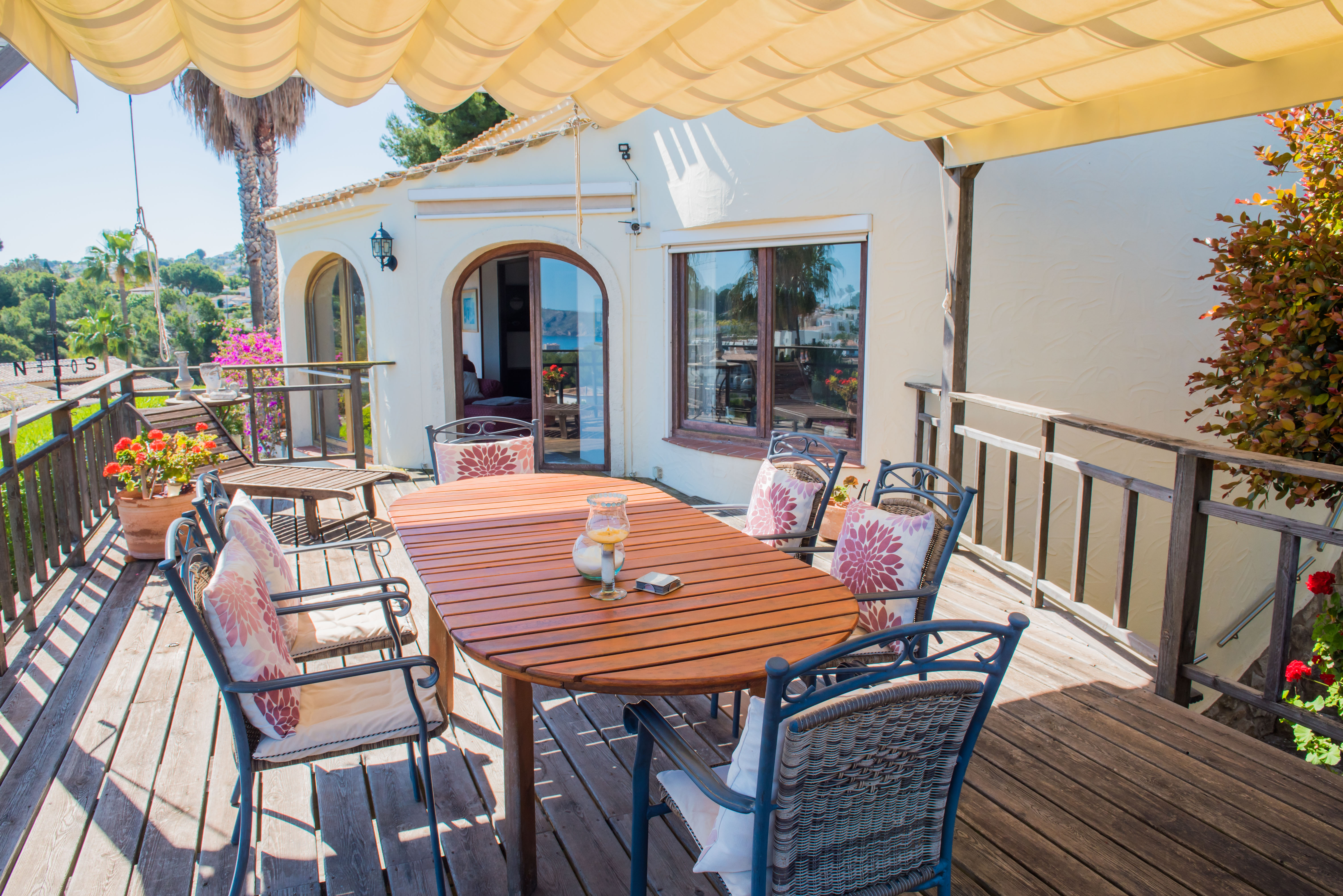 Überdachte Terrasse mit Holztisch und gepolsterten Stühlen, ideal, um den Panoramablick auf das Mittelmeer zu genießen.