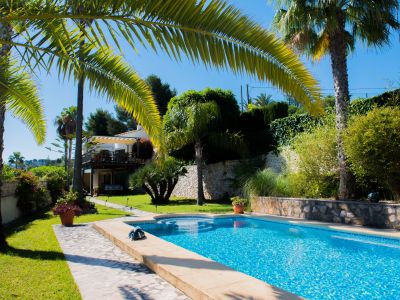 Blick auf den blau gefliesten Pool und den mediterranen Garten mit Palmen in Jávea.