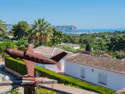 Panoramablick auf Jávea von der Terrasse, mit einer Flugzeugskulptur im Vordergrund und üppigem Grün.