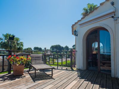Sonnige Terrasse mit Holzboden, Liegestuhl und Blick auf die mediterrane Landschaft.