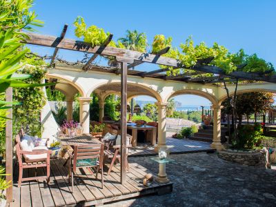Terrasse mit holzgedeckter Pergola und Steinbögen mit Blick auf das Mittelmeer.