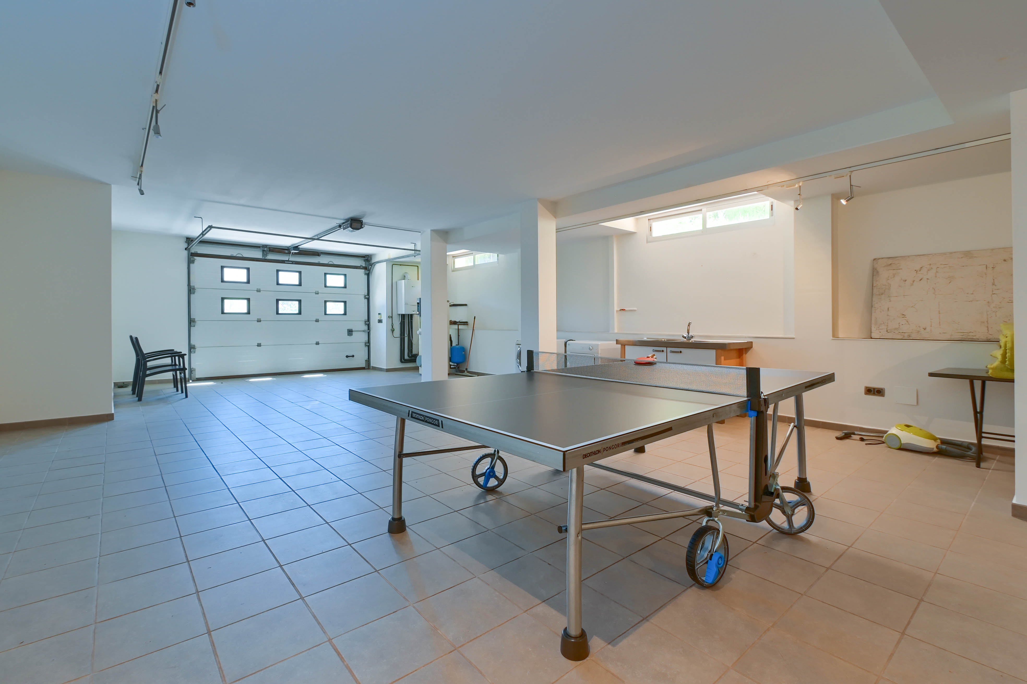 Freizeitraum mit Decathlon Pongori Tischtennisplatte, Fliesenboden und Zugang zur Garage.