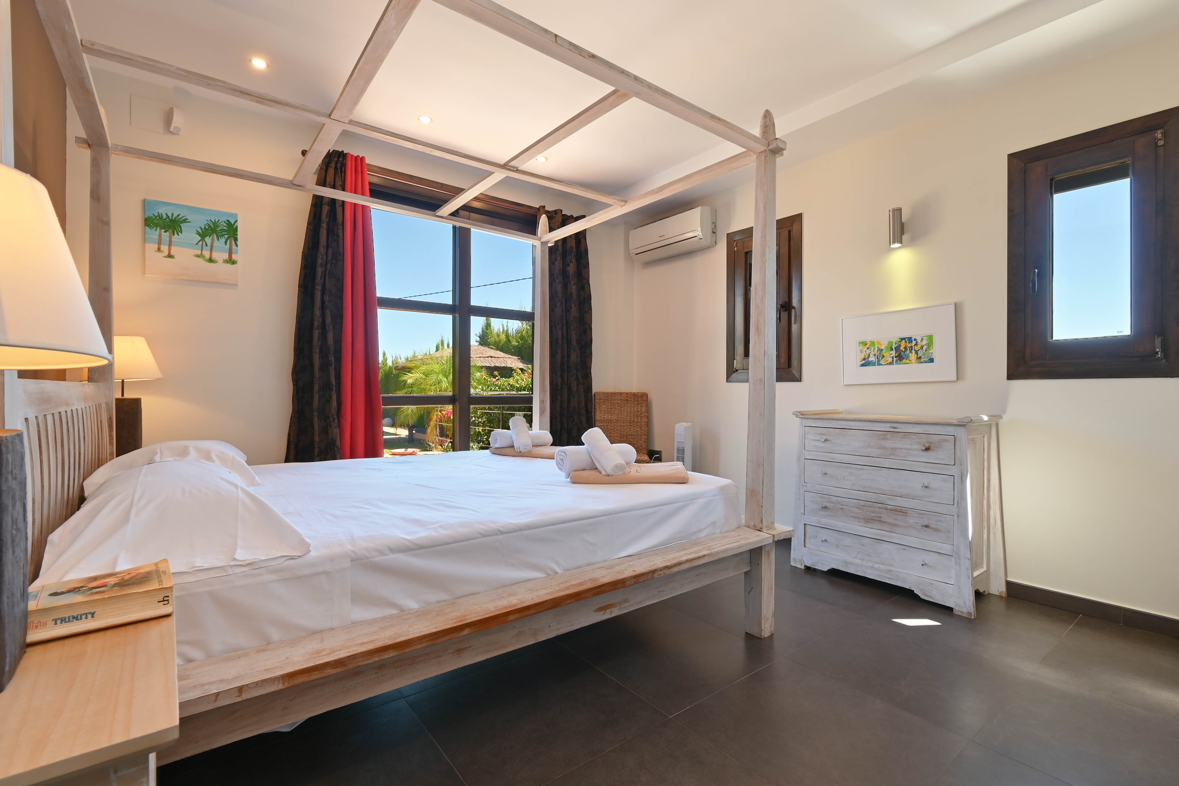 Helles Schlafzimmer mit hellem Holzhimmelbett und weißer Kommode im Used-Look.