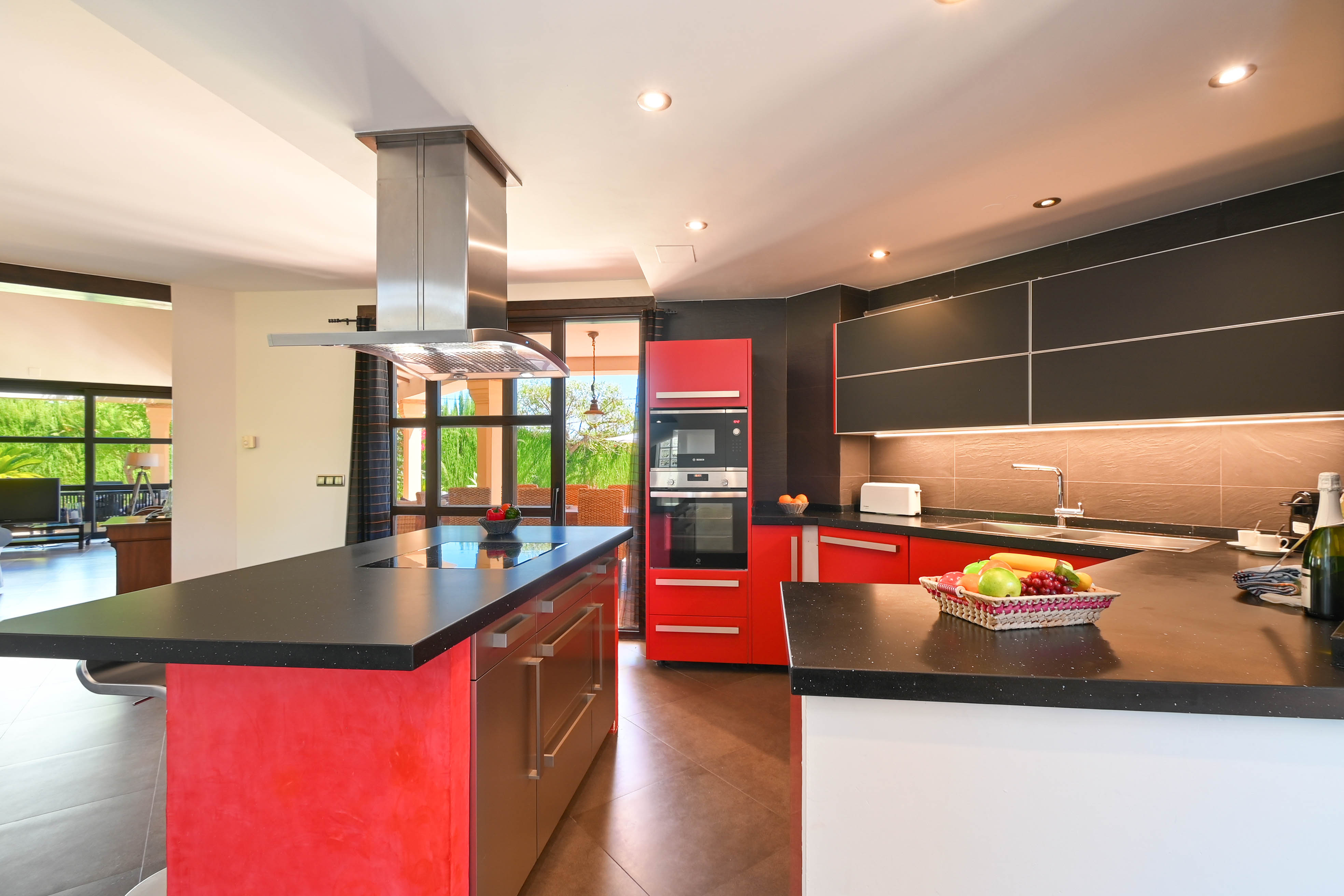 Moderne Küche mit schwarzen Granit-Arbeitsplatten, roten und schwarzen Schränken und Edelstahlgeräten.