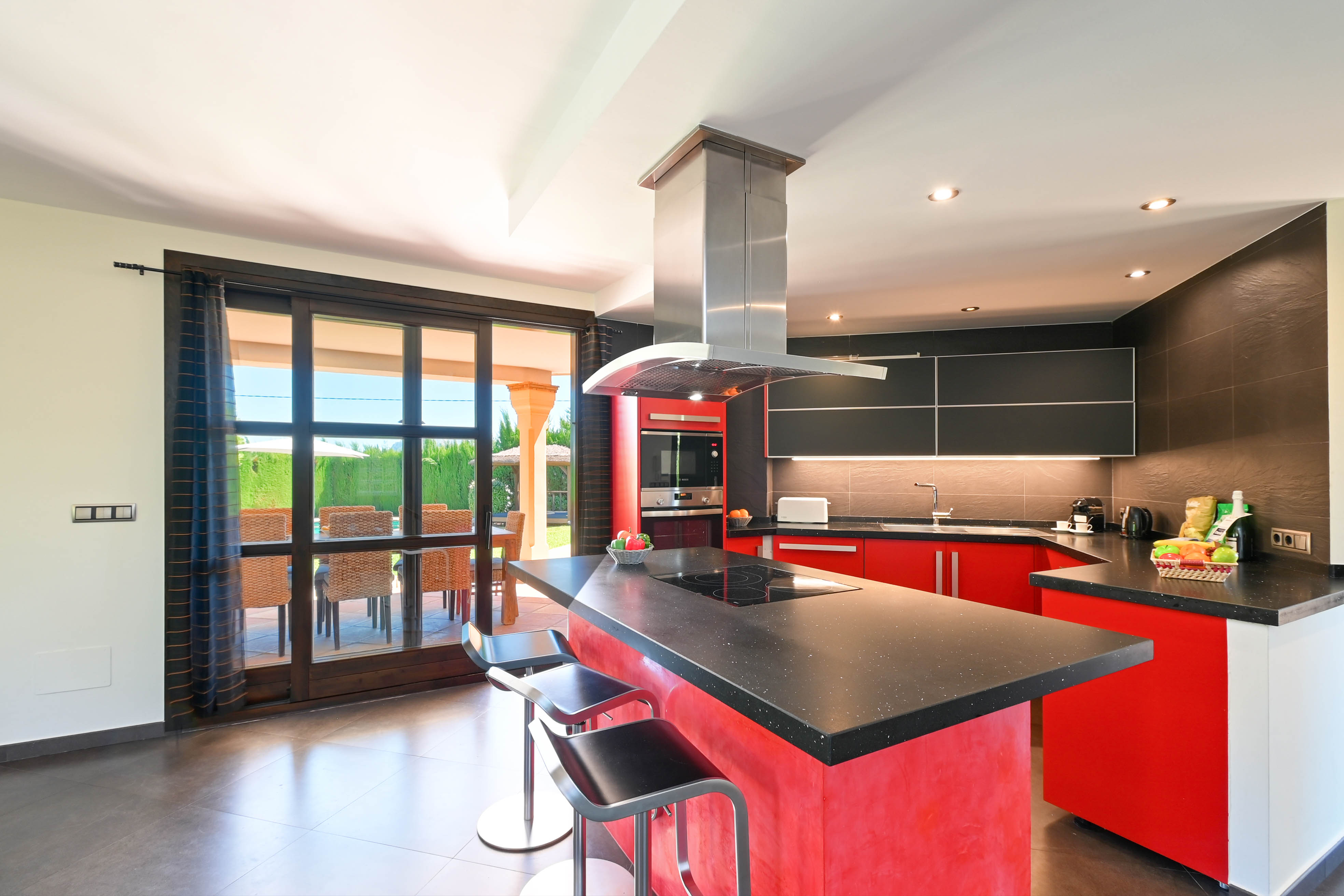 Moderne Küche mit zentraler Insel, schwarzer Granitarbeitsplatte und Metallhockern.