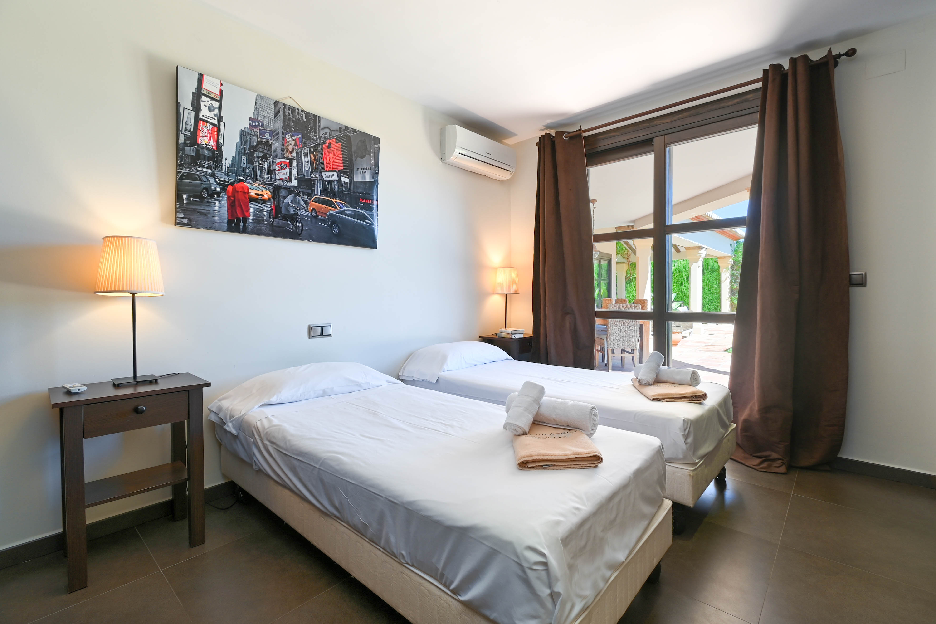 Schlafzimmer mit zwei Einzelbetten, weißer Bettwäsche und Blick nach draußen.
