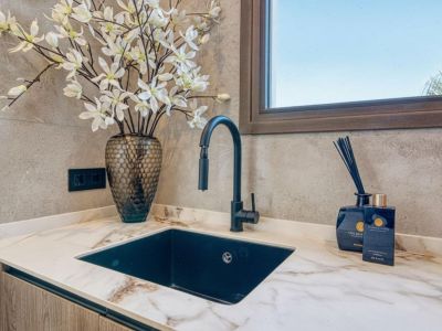 Detail der Arbeitsplatte mit schwarzem Waschbecken, modernem Wasserhahn und Blumendekor. Eleganz und Funktionalität in der Küche.