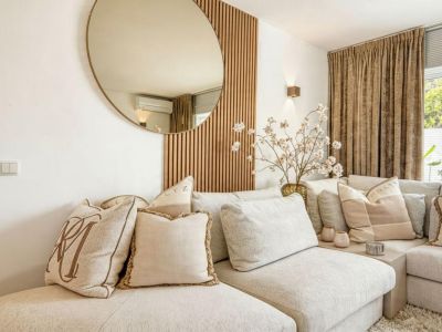 Detail des Wohnzimmers mit beigefarbenem modularem Sofa und dekorativer Holzwand.