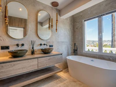 Elegantes Badezimmer mit Steinwaschbecken auf einer Holzplatte, freistehender Badewanne und Panoramablick.