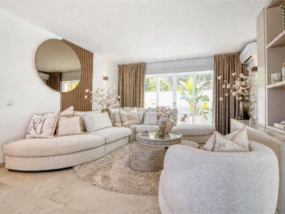 Helles Wohnzimmer mit beigem Ecksofa, flauschigem Teppich und dekorativem runden Spiegel.