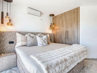 Schlafzimmer mit strukturiertem Kopfteil, Designer-Pendelleuchten und Einbauschrank aus hellem Holz.