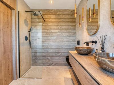 Stilvolles Badezimmer mit Steinwaschbecken und gläserner Dusche, hervorzuheben sind die geometrisch gemusterten Wandfliesen.