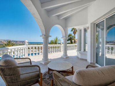 Überdachte Terrasse mit Steinbögen, Rattanmöbeln und Panoramablick auf das Mittelmeer.