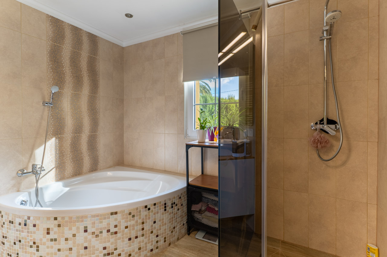 Badezimmerdetail mit Mosaik-Eckbadewanne und gläserner Duschkabine.