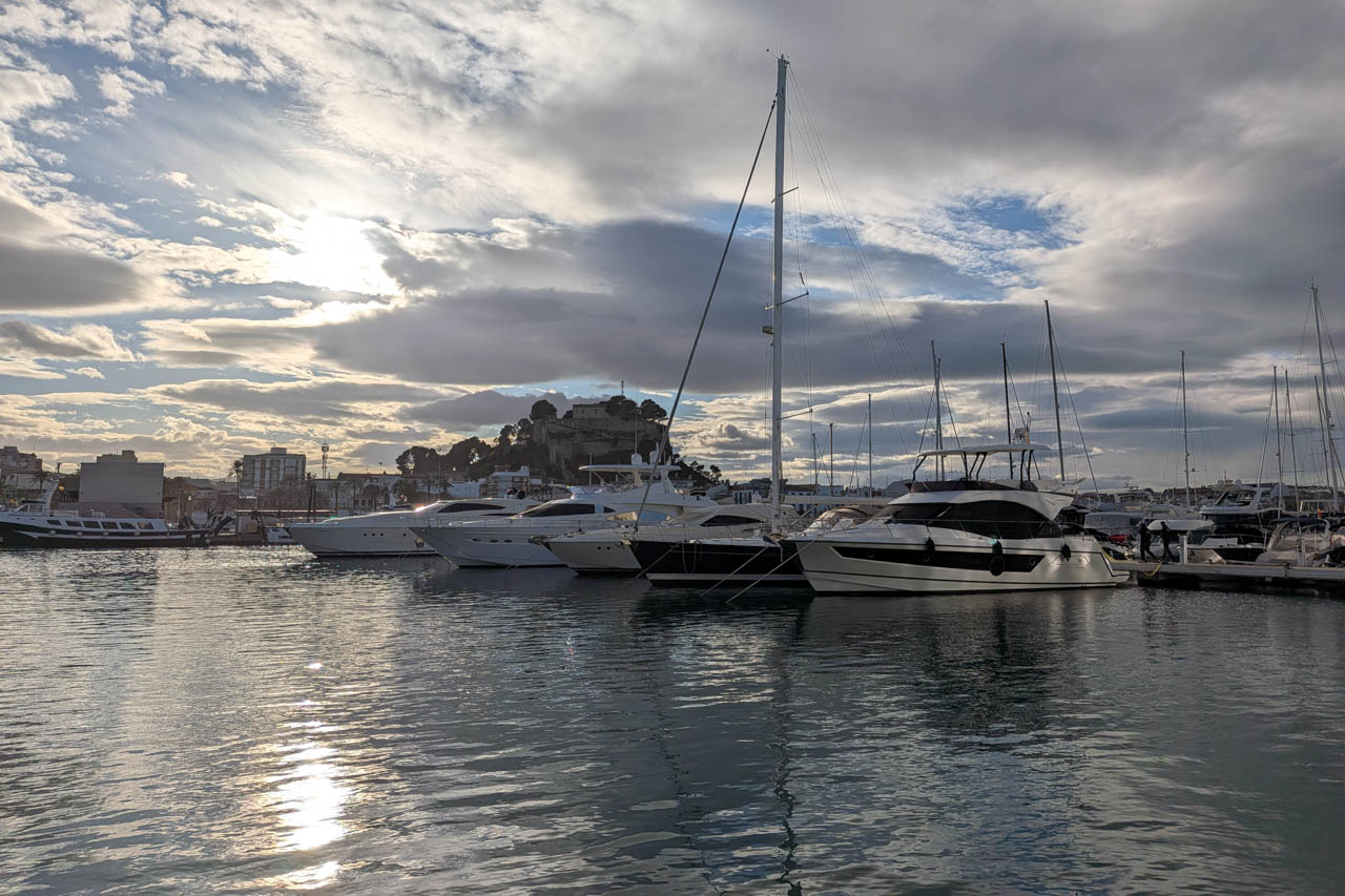 Blick auf den Yachthafen mit Yachten und Sonnenreflexionen auf dem Wasser.