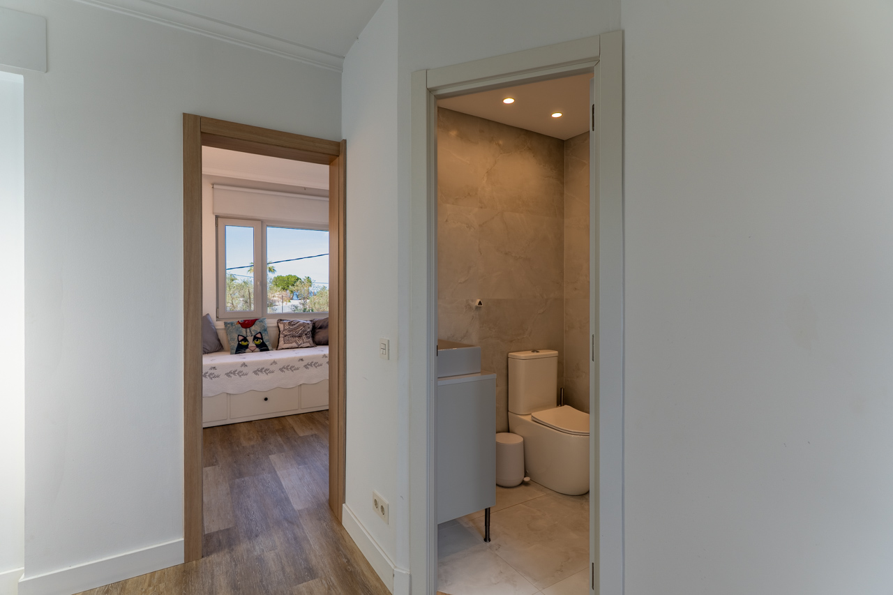 Flurdetail mit Zugang zu Marmorbad und hellem Schlafzimmer.