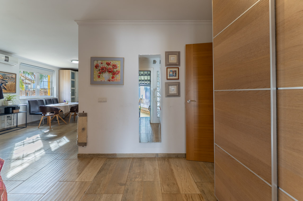 Heller Eingangsbereich mit Keramikfliesen in Holzoptik und Wanddekoration.