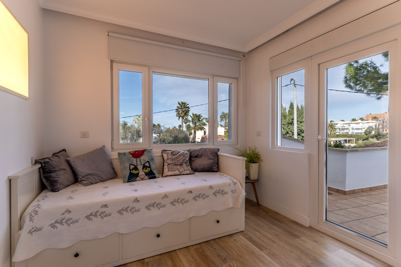 Helles Schlafzimmer mit Tagesbett, Außenansicht und Zugang zur Terrasse.