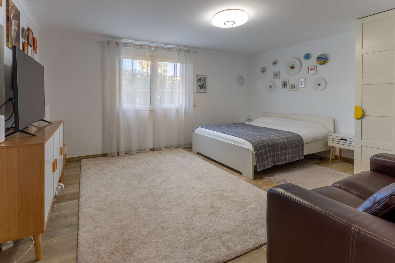 Helles Schlafzimmer mit weißem Bett, weichem Teppich und dekorativer Wandkunst.