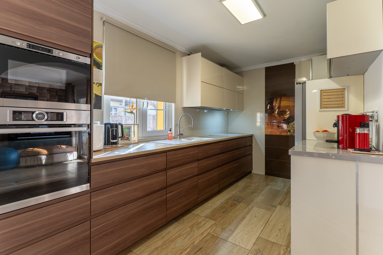 Moderne Küche mit Holzschränken, heller Arbeitsplatte und Fliesen in Holzoptik.