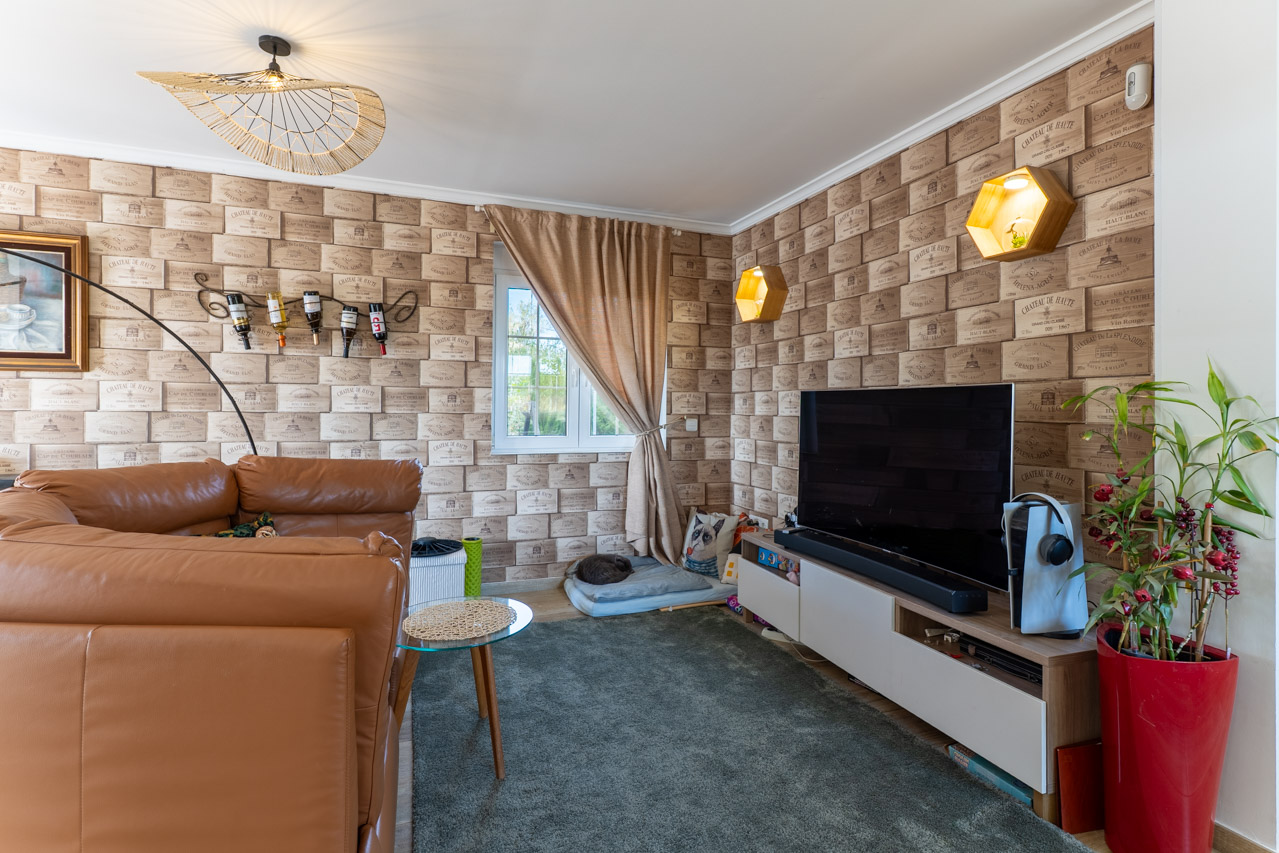 Wohnzimmer mit Weinkisten-Tapete und braunem Ledersofa.